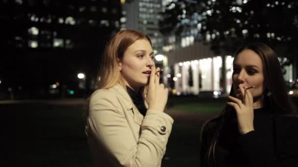 Duas belas jovens mulheres fumam cigarros, sugando fumaça em seus pulmões — Vídeo de Stock