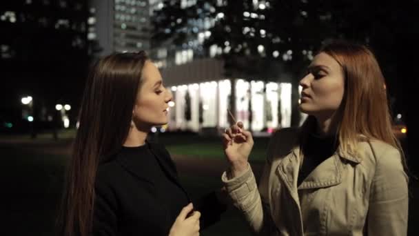 Roodharig meisje inhaleert rook van sigaret, geeft het aan haar brunette vriendin. — Stockvideo