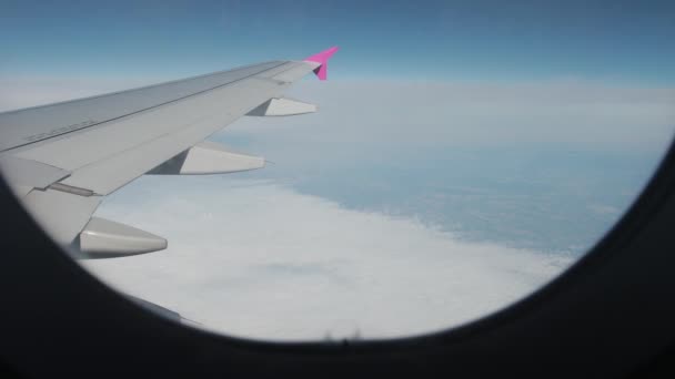 遠くの地面に雲と素晴らしい景色、飛行機のイルミネーターからの空. — ストック動画