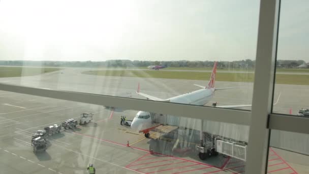 Embarque del avión a través del puente jet. Vista desde la ventana de cristal del terminal . — Vídeos de Stock