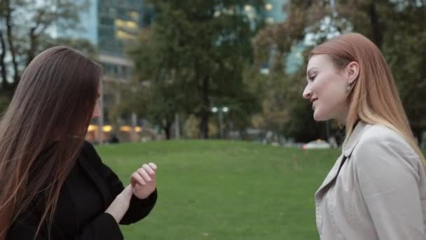 Duas jovens garotas atraentes comeram conversando no parque da cidade . — Vídeo de Stock