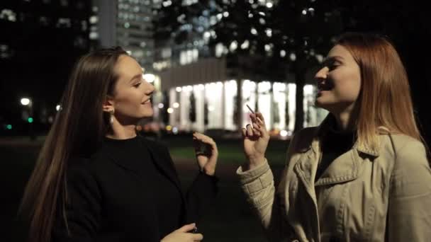 Рыжая женщина курит и смеется, ее подруга брюнетка показывает удовлетворенное лицо — стоковое видео
