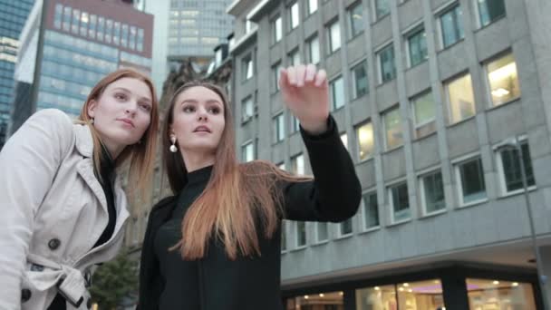 Två unga attraktiva kvinnor i eleganta casual kläder talar i centrum av staden. — Stockvideo