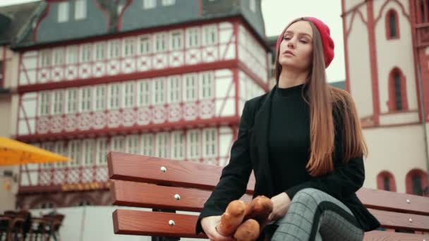 Franse vrouw in zwarte jas zit met lange broden verpakt in papier — Stockvideo
