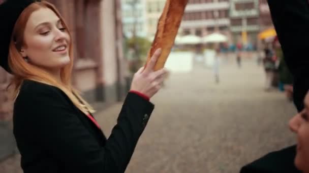 Две красивые француженки в черных куртках и красном берете дерутся хлебами , — стоковое видео