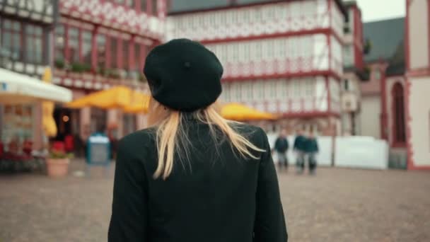 Стильная женщина с рыжими волосами, идущая по улице, счастливо смотрит на камеру — стоковое видео