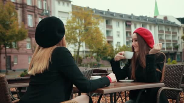 Δύο όμορφες σαγηνευτικές Γαλλίδες κάθονται στο δρόμο και πίνουν καφέ. — Αρχείο Βίντεο