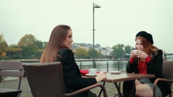 Two beautiful seductive women French sit on the street and drink coffee — Stock Video