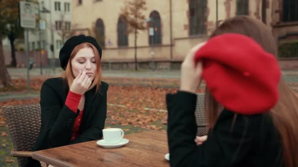 Két gyönyörű, csábító nő, francia ül az utcán és kávézik. — Stock videók