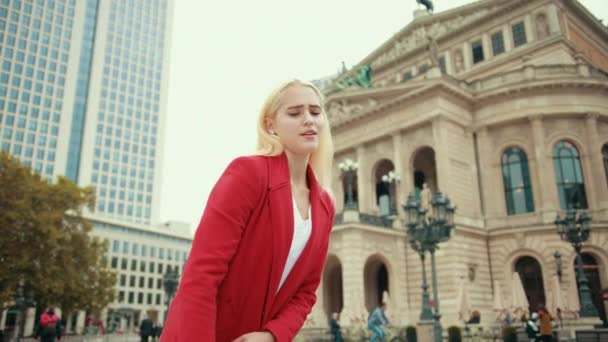 Piękna blondynka w czerwonej kurtce podnosi ciężką dużą torbę — Wideo stockowe