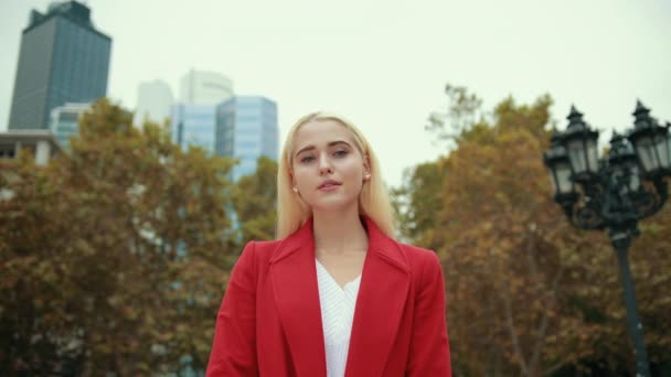 Portrait blonde girl who looks at camera dressed in white sweater and red jacket — Stock Video