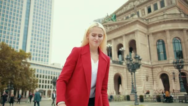 Schöne blonde Frau in roter Jacke hebt schwere große Tasche auf — Stockvideo