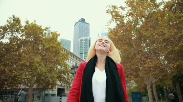 Chica rubia en el fondo de la ciudad moderna va hacia adelante gira delante de la cámara — Vídeos de Stock