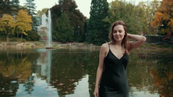 Kvinnlig modell går över bron över piren vid sjön i Botaniska trädgården spinning — Stockvideo
