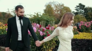 Birbirine aşık yeni evliler. Beyaz gelinlik giymiş gelin damadın elini tutuyor.