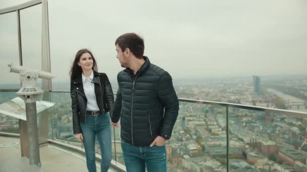 Man holds hand of woman leads her behind him on roof of tall house — Stock Video