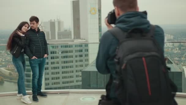 Par poserar framför professionell fotograf på taket av höga hus — Stockvideo