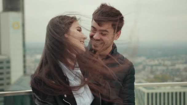 Couple of young people embrace on roof of tall house in city of megapolis. — Stock Video