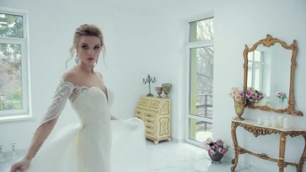 Молодая блондинка невеста в белом свадебном платье позирует перед камерой, поворачивается — стоковое видео
