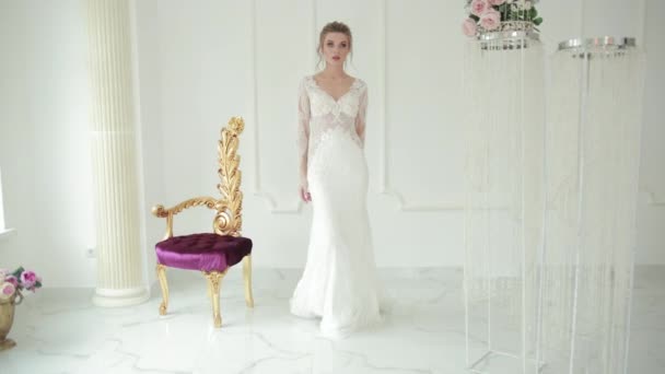 Noiva loira no vestido de casamento estilo sereia branca caminha para a frente toques para se vestir — Vídeo de Stock