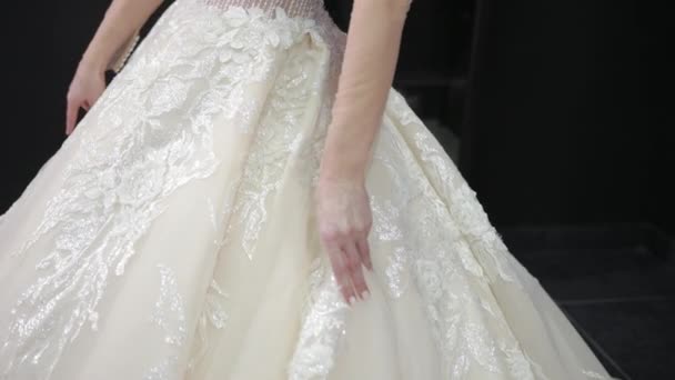 Close-up of white wedding dress that bride is wearing, touches tulle makes wave — Stock Video