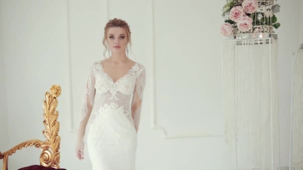 Молода блондинка в білій весільній сукні позує для обертання камери навколо . — стокове відео
