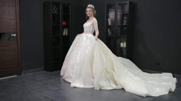 Blonde bride in white wedding dress with crown on her head is walking forward — 图库视频影像