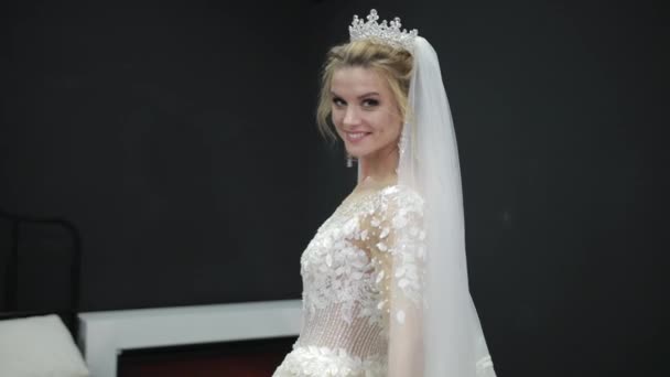 Bride in white wedding dress with veil walks through room black walls smiles — Stockvideo