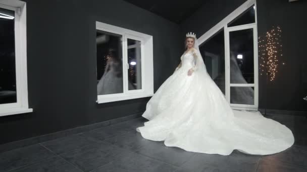 Novia con corona en la cabeza está de pie en vestido de novia blanco que brilla sonrisas — Vídeos de Stock