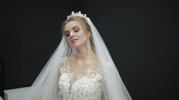 Mladá krásná nevěsta v bílých svatebních šatech hraje se závojem dělat vlny — Stock video