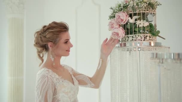 Primer plano de novia rubia en vestido blanco posando para la cámara, tocando la flor — Vídeos de Stock