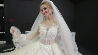 beautiful bride in white dress plays with veil smiles makes wave with hands.