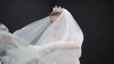Young bride in white wedding dress plays with veil making waves smiling camera