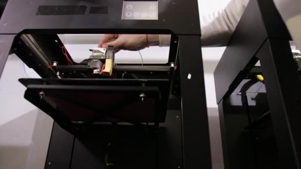 Tecnología 3D un hombre joven inserta hilo de cable amarillo en la impresora . — Vídeos de Stock