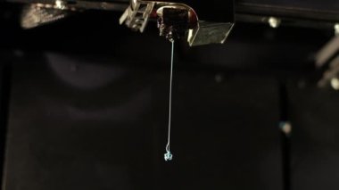 3D printer technology head prints red part from plastic cable thread close up.