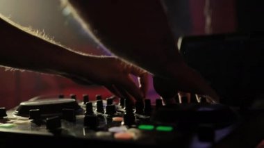 Bir gece kulübünde DJ çalışıyor, müzikle uzaktan kumandayı karıştırıyor..