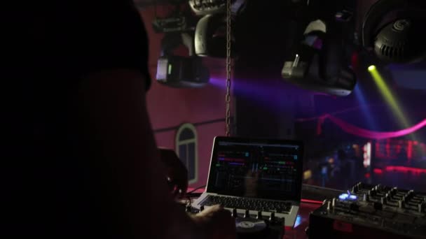 DJ en un club nocturno funciona, mezcla música con un control remoto . — Vídeo de stock