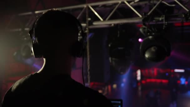 DJ in einem Nachtclub arbeitet, mischt Musik mit einer Fernbedienung. — Stockvideo