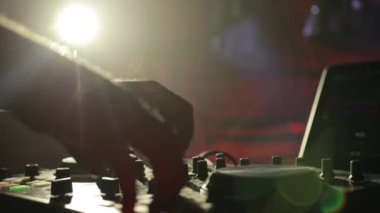 Bir gece kulübünde DJ çalışıyor, müzikle uzaktan kumandayı karıştırıyor..