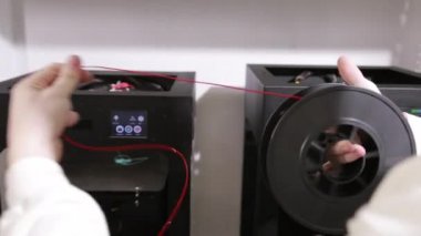 young man unwinds and extracts a red plastic thread cable from the coil.