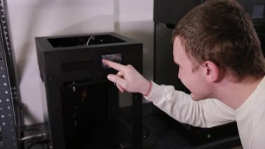 3D technology man presses the printers buttons preparing it for printing