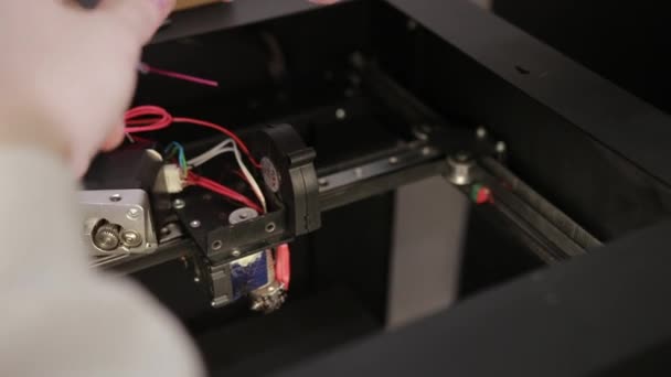 Mladý muž opravuje 3D tiskárnu opravuje detaily ladící práce. — Stock video