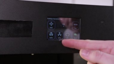 3D technology mans hand presses the printers buttons preparing it for printing
