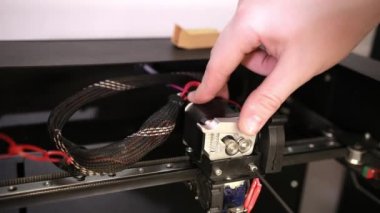 young man repairs 3D printer repairs the details of debugging work.