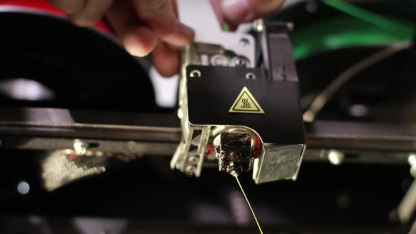 Żółty plastikowy gwint drukowany przez głowicę drukarek 3D przesuwa zielony kabel — Wideo stockowe