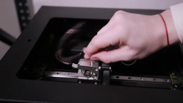 3d technologie twee mannen handen duwen een plastic witte draad in tanden van de printer — Stockvideo