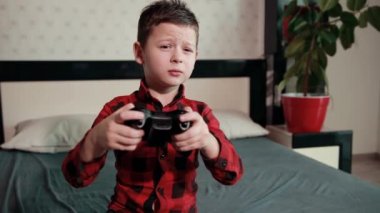 Sevimli çocuk video oyunu oynuyor, elinde joystick tutuyor, duygusal zaman geçiriyor.