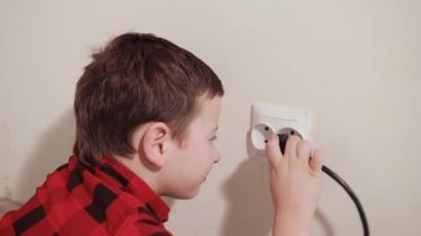 cute guy rubs his hands, pushes an electric plug into socket