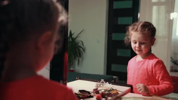 Маленькая милая девочка в розовом платье расчесывает волосы расческой — стоковое видео