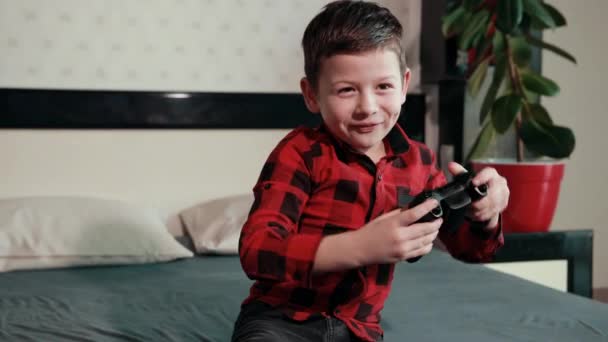 Cute boy playing video game, holding joystick, having an emotional time — Stock Video